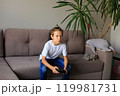A young boy is fully immersed in playing a video game on the television, showcasing a range of emotions from excitement to concentration. His facial expressions reflect the thrill of the game 119981731