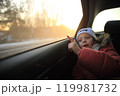 a child sitting in a car, gazing thoughtfully out the window. The soft light illuminates the child's face, highlighting a sense of wonder and curiosity as they observe the world passing by.  119981732