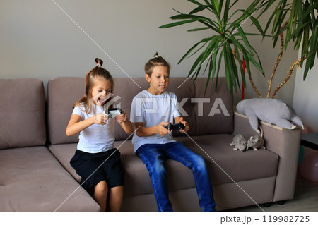 A lively scene of a boy and girl enthusiastically playing video games together at home. they immerse themselves in the gaming experience, highlighting the joy of childhood and the importance of 119982725