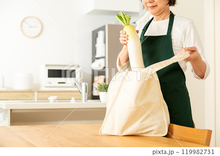 家のリビングでマイバックから食材を取り出すミドル〜シニア女性 家のリビングでマイバックから食材を取り出すミドル〜シニア女性 119982731