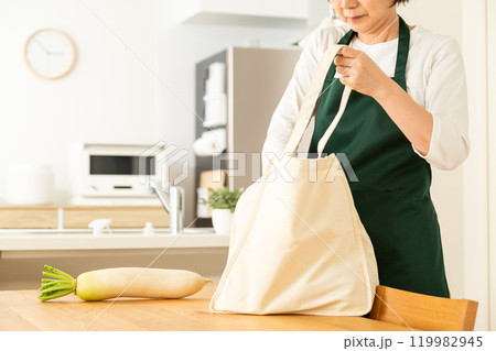 家のリビングでマイバックから食材を取り出すミドル〜シニア女性 119982945