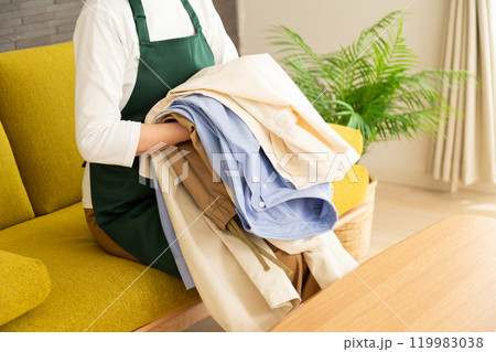 リビングのソファーで洗濯物を畳むエプロンをしたミドル〜シニア女性 リビングのソファーで洗濯物を畳むエプロンをしたミドル〜シニア女性 119983038