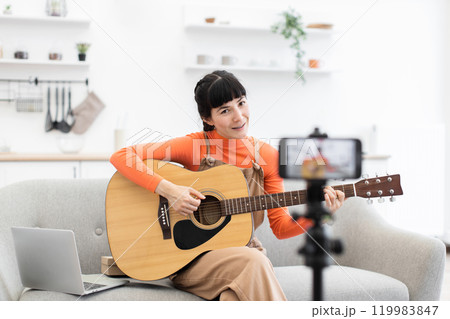 Woman teaching online guitar course from cozy home setting 119983847