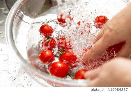 家のキッチンでミニトマトを水洗いするミドル〜シニア女性の手元 119984887