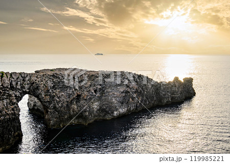 Spectacular sunset at Pont d'en Gil, Cala Corbetar, in Ciutadella, Menorca, Balearic Islands. Peculiar natural formation in the form of an arch Spectacular sunset at Pont d'en Gil, Cala Corbetar, in Ciutadella, Menorca, Balearic Islands. Peculiar natural formation in the form of an arch 119985221