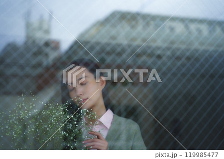 ガラス越しに写る街並みと物憂げな表情の若い女性 ガラス越しに写る街並みと物憂げな表情の若い女性 119985477