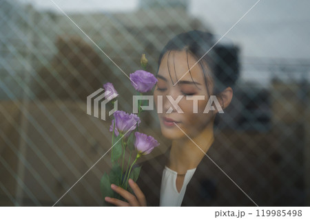 ガラス越しに写る街並みと物憂げな表情の若いスーツ女性 119985498