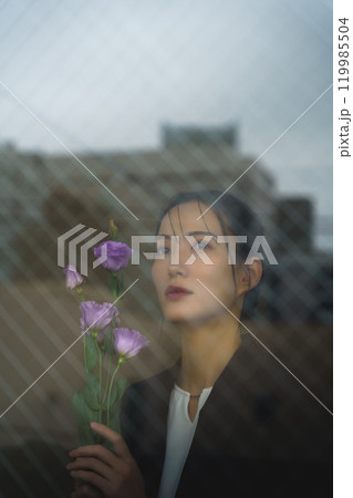 ガラス越しに写る街並みと物憂げな表情の若いスーツ女性 119985504