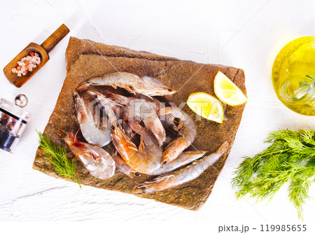 Raw tiger white shrimp prawn on board with herbs. 119985655