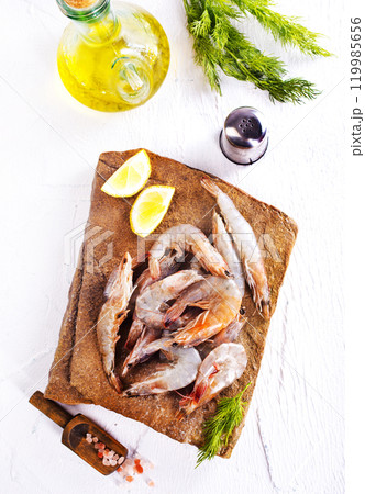 Raw tiger white shrimp prawn on board with herbs. 119985656