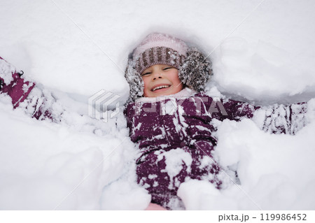 Little girl covered in snow, laughing and playing. A perfect scene of childhood excitement in a winter wonderland 119986452