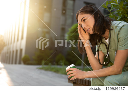 Dark-haired young female doctor feeling tired after the night shift 119986487
