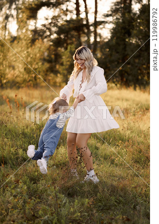 Happy Caucasian mother holding her baby in the air on a walk in a summer park Happy Caucasian mother holding her baby in the air on a walk in a summer park 119986792