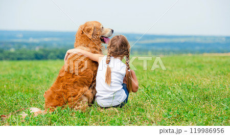 Little girl hugging retriever in the field, looking into the distance 119986956