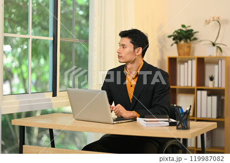 Thoughtful businessman looking out the window contemplating new ideas in office 119987082