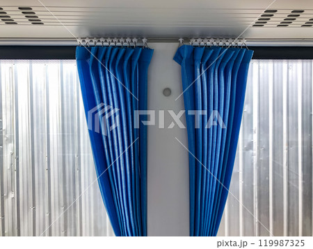 Shot of blue curtains installed on the windows of new air conditioned bus in second layer of white curtains background. 119987325