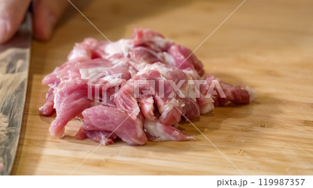 Close up of chef Butcher cutting pork meat with knife on kitchen, cooking food. The chef butcher preparing pork meat for cooking. 119987357