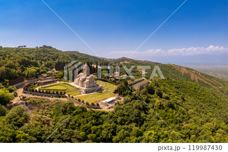 Aerial top view of the Bodbe Monastery architectural complex of St. Nino. View from above to church, Alazani Valley, Greater Caucasus mountains, in sunny summer day. Sighnaghi city, Kakheti, Georgia. 119987430