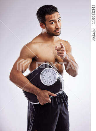 Pointing, portrait and man with scale for fitness in studio for body care, wellness and diet for muscles. Male person, athlete or bodybuilder and smile for weight loss or exercise by white background Pointing, portrait and man with scale for fitness in studio for body care, wellness and diet for muscles. Male person, athlete or bodybuilder and smile for weight loss or exercise by white background 119988345