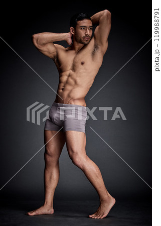 Fitness, asian man and bodybuilder flexing abs and strong body in sexy underwear isolated in studio. Health, seductive and male person with stomach muscles from training and workout challenge 119988791