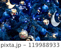 Background of silver, mirror, blue balls toys and lights on blue indoor Christmas tree for New Year 119988933