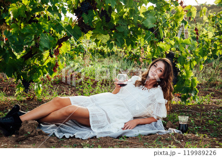 Beautiful woman with a glass of vine in the vineyard before harvesting with a smile Beautiful woman with a glass of vine in the vineyard before harvesting with a smile 119989226