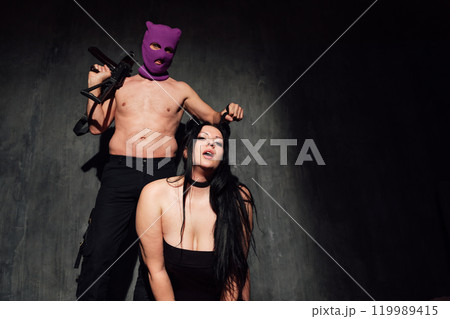man and woman in black lingerie on dark background with guns man and woman in black lingerie on dark background with guns 119989415