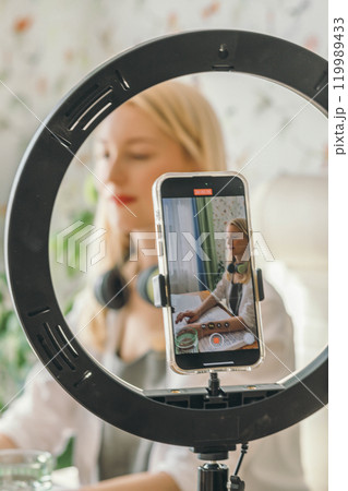 Freelancer using digital tools and lighting to maintain a strong professional brand while working remotely, video with ring lamp 119989433