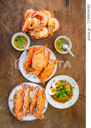 Top view Boiled Crabs and Shrimps in the white ceramic and glass dish on the vintage wooden table. Top view Boiled Crabs and Shrimps in the white ceramic and glass dish on the vintage wooden table. 119989498