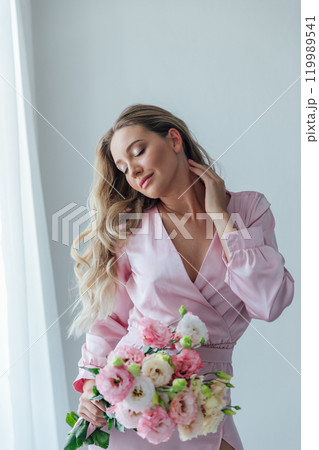 Beautiful fashionable woman in summer pink dress with flowers looking in the mirror 119989541