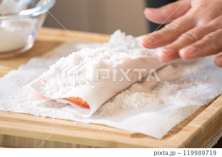 Marinated Salmon with Salt on paper tissue food grade on Wooden cutting plate by Professional hand Chef. Marinated Salmon with Salt on paper tissue food grade on Wooden cutting plate by Professional hand Chef. 119989719