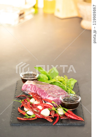 Raw Beef and herb ingredients, basil leaf, garlic, chilli, sauces are prepared on a black stone, slate plate for next cooking process in the Thai food menu, Stir-fried beef basil. 119989867