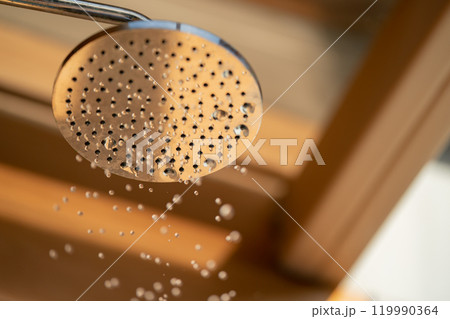 Close up to Outdoor shower head for the bath and showering cold water to body before jumping in the resort pool. 119990364