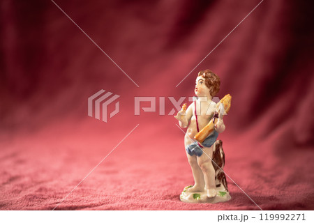 毛足のある赤い布の上に置いた、小さな男の子の陶器製アンティークドール 119992271