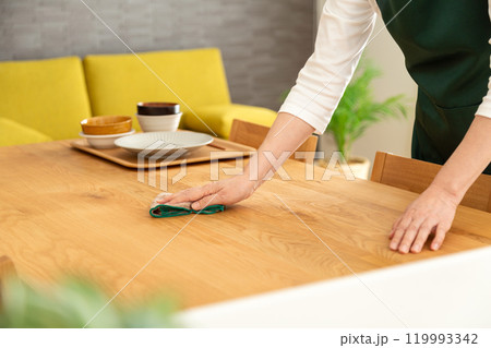 食器の後片付けをしてテーブルを拭くミドル〜シニア女性の手元 119993342