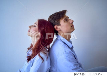 siblings, young adult brother and teenage sister sitting back to back siblings, young adult brother and teenage sister sitting back to back 119993528