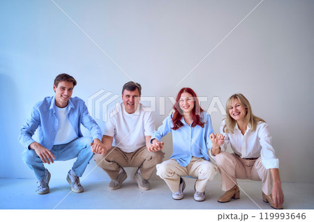 a family, middle-aged husband and wife, young adult son and teenage daughter, squatting on a white background, studio photo shoot 119993646