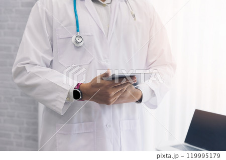 Doctor standing with stethoscope and holding tablet computer. Technology and medical concept. Doctor standing with stethoscope and holding tablet computer. Technology and medical concept. 119995179