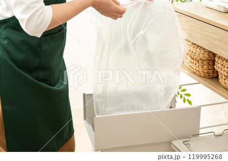 キッチンのゴミ箱にゴミ袋をセットするミドル〜シニア女性の手元 119995268