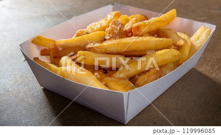 a white paper box filled with golden brown French fries a white paper box filled with golden brown French fries 119996085