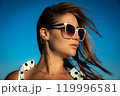Portrait Young woman in white polka dot dress and sunglasses posing against the backdrop of the sky. Close-up 119996581