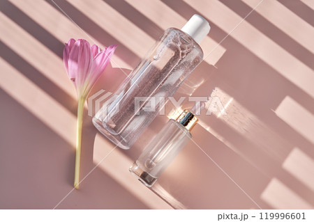 Bottle of facial toner or cleanser on a pink background with stripes shadows. Bottle of facial toner or cleanser on a pink background with stripes shadows. 119996601