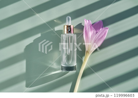 Bottle of cosmetic serum with pipette on green background with shadow stripes. 119996603