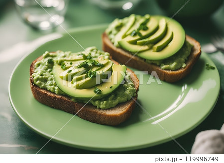 Board of tasty avocado toasts on green plate 119996749