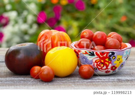 Variety of tomatoes, big and small, on the wooden table in the garden. 119998213