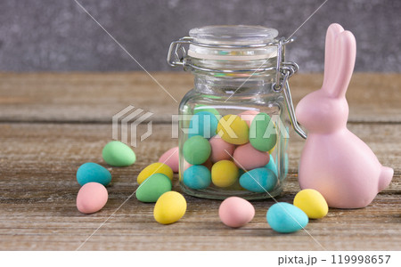 Easter composition with pink bunny and a jar with colorful candies. 119998657