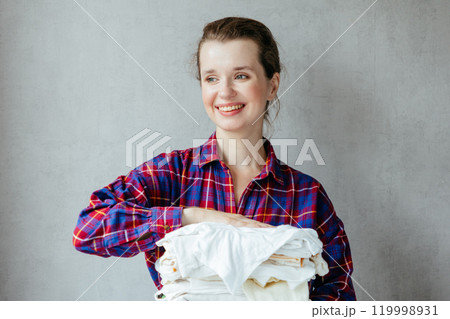 happy woman holds stack of clean white clothes in hands after washing, drying. 119998931