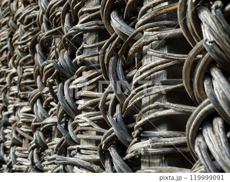 A close view of an old rustic fence made from intertwined natural materials A close view of an old rustic fence made from intertwined natural materials 119999091