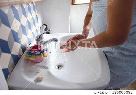 Woman washing hands in bathroom with colorful decor 120000086