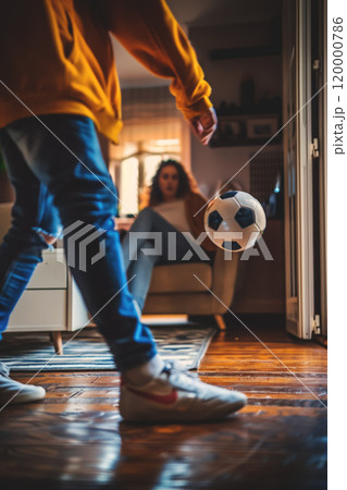 husband playing soccer with wife at home, man play football with woman at living room, person kick ball 120000786